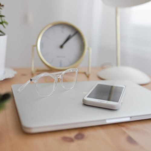 Image of a desk with clock and closed laptop